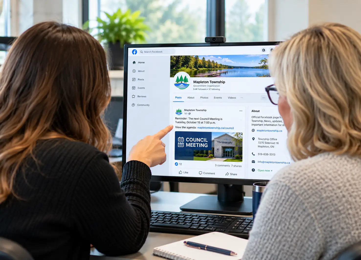 Two municipal staff members reviewing and discussing a township social media page on a computer.